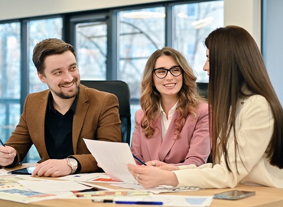 Absoft employees in a modern Absoft office setting discuss documents and charts, symbolizing the company’s deep expertise and collaborative approach to SAP payroll solutions.