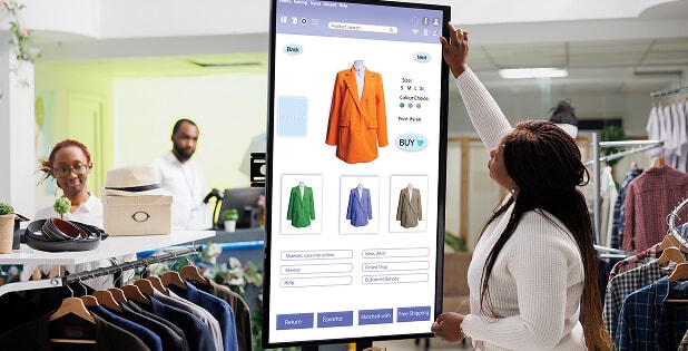 Person viewing a digital display of clothing items in a fashion store, representing tech-enabled vertical integration with SAP S/4HANA Fashion